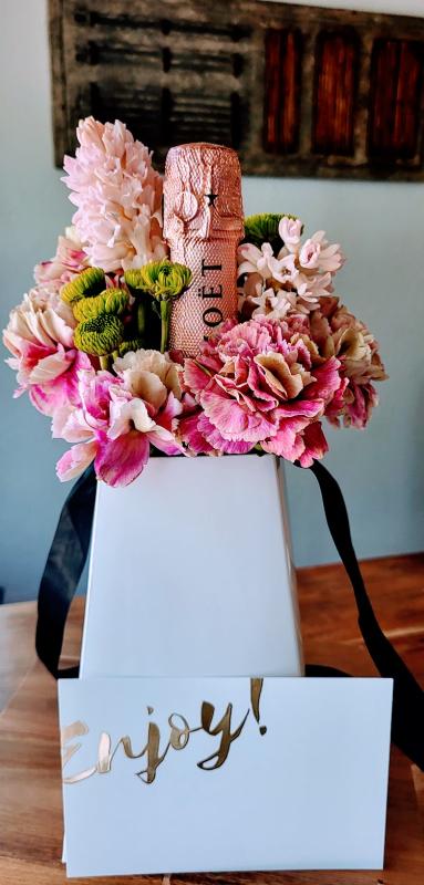 A cute and unique gift bag of Champagne bottle with fresh bouquet to cheer someone with.